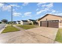 Tan house with brown double garage door and green lawn at 2463 Hybrid Dr, Kissimmee, FL 34758