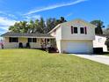 Charming two-story home featuring a well-manicured lawn, two-car garage, and colorful landscaping at 506 Little Wekiva Rd, Altamonte Springs, FL 32714