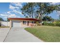 Ranch home with a white garage door and a long driveway at 716 Katherine St, South Daytona, FL 32119
