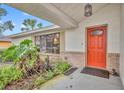 Orange front door entry with brick and plant accents at 817 W 9Th St, Deltona, FL 32725