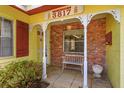 Inviting front porch with brick columns and a quaint white bench at 3817 Bainbridge Ave, Orlando, FL 32839