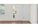 Bright entryway featuring wood-look flooring, a classic white front door flanked by sidelights and a nearby window at 14735 Sw 69Th Court Rd, Ocala, FL 34473