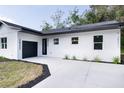 The house has a modern design with a black garage door and a well-manicured lawn with new plantings at 2033 N Orange St, Mount Dora, FL 32757