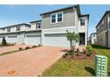 Exterior view of gray two-story townhomes featuring manicured lawns and brick driveways at 4329 Switchgrass Ln, St Cloud, FL 34772