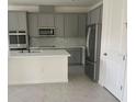 Modern kitchen with stainless steel appliances, gray cabinetry, and a stylish tile backsplash at 5374 Lake Virginia St, Winter Garden, FL 34787