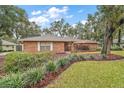 Brick home with mature trees and well-manicured lawn at 9908 Fairway Cir, Leesburg, FL 34788