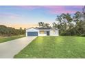 White house with a gray garage door, set against a vibrant sunset at 14 Fisher Loop Pass, Ocklawaha, FL 32179