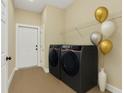 Modern laundry room features sleek, front-load washer and dryer, plus a stylish vase and decorative balloons at 14 Fisher Loop Pass, Ocklawaha, FL 32179