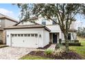 Two-story house with a beige exterior, a three-car garage, and a landscaped front yard at 1498 Moon Valley Dr, Davenport, FL 33896