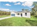 New construction home, featuring a gray garage door and a well-manicured lawn at 18 Malauka Pass Ter, Ocklawaha, FL 32179