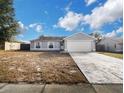 Front view of a gray house with a white garage door and a spacious lawn at 255 Autumn Ridge Rd, Deltona, FL 32725