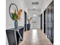 Inviting hallway featuring dark doors, ceramic tile floor, decorative table, and modern mirror at 3012 Penelope Loop, Kissimmee, FL 34746