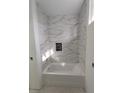 Modern bathroom featuring a white bathtub and marble-style tile at 313 Bass Ct, Kissimmee, FL 34759