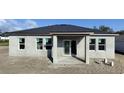 Rear view of a new construction home with sliding glass doors leading to a covered patio at 313 Bass Ct, Kissimmee, FL 34759