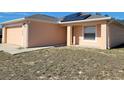 Tan house with a two-car garage and solar panels on the roof at 1238 Conch Key Ln, Davenport, FL 33837