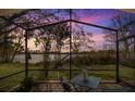 Relaxing screened patio overlooking a serene lake at sunset at 452 Misty Oaks Run, Casselberry, FL 32707