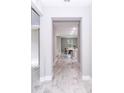 View down light and airy entryway with stylish light-colored wood-look flooring into kitchen and living area at 7542 Sw 128 Terrace Rd, Dunnellon, FL 34432
