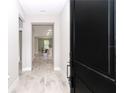 View from black front door down light and airy entryway with stylish light-colored wood-look flooring at 7542 Sw 128 Terrace Rd, Dunnellon, FL 34432