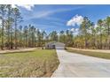Wide angle showing gray single story home with long driveway set amongst mature trees at 7542 Sw 128 Terrace Rd, Dunnellon, FL 34432