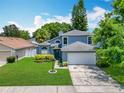 Charming two-story home with a manicured lawn, lush landscaping, and an attached two-car garage at 13111 Point O Wood Ct, Orlando, FL 32828