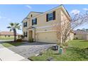 Two-story house, tan exterior, brown accents, paved driveway, and landscaping at 1504 Oak Marsh Loop, Davenport, FL 33837