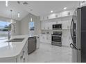 Modern kitchen features white cabinets, stainless steel appliances, pendant lights, and a large island at 1700 Underwood Ave, St Cloud, FL 34771