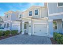 Two-story townhome with gray siding, paver driveway, and landscaping at 4708 Tribute Trl, Kissimmee, FL 34746