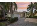 Charming home with lush landscaping, brick driveway, and a tile roof provides curb appeal with an amazing sunset at 12161 Obelia Ln, Orlando, FL 32827