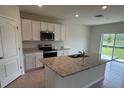 Bright, modern kitchen features granite countertops, stainless steel appliances, and an island with a sink at 2212 Lake Preserve Cir, New Smyrna Beach, FL 32168