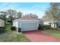 Front view of a light green house with a red brick driveway and lush landscaping at 2311 Caledonian St, Clermont, FL 34711