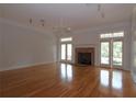 Spacious living room featuring hardwood floors, a brick fireplace, and bright double doors at 34122 Park Ln, Leesburg, FL 34788