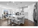 A modern white kitchen features an island with seating, stainless steel appliances, and hardwood floors at 4485 Lions Gate Ave, Clermont, FL 34711