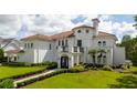 White two-story house with a tile roof, lush landscaping, and gated entry at 717 Eastlawn Dr, Kissimmee, FL 34747