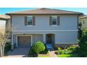 Two-story townhome with brown shutters, tile roof, a garage and green landscaping in front at 1312 Shinnecock Hills Dr, Davenport, FL 33896