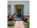 Inviting front entryway with a brick walkway and lush tropical plants at 1312 Shinnecock Hills Dr, Davenport, FL 33896