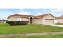 Tan one-story house with a two-car garage and a neatly landscaped yard at 2543 Sage Dr, Kissimmee, FL 34758