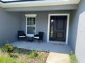 Covered front porch with black door and two wicker chairs at 943 Derbyshire Dr, Kissimmee, FL 34758