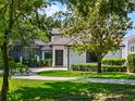 Charming two-story home with a neutral facade, a covered entrance, and a lush green lawn with mature trees at 9697 Bryanston Dr, Orlando, FL 32827