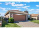 Tan house with a brown garage door and brick driveway at 125 Silver Maple Rd, Groveland, FL 34736