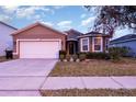 House exterior featuring a two-car garage and well-manicured lawn at 1569 Tamarind Rd, Davenport, FL 33896