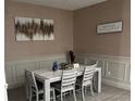 Bright dining room with table and chairs, wall art, and wainscoting at 16368 Orange Seed Ln, Winter Garden, FL 34787