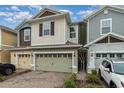 Two-story townhome with a light green garage door and landscaped front yard at 2583 Sedge Grass Way, Orlando, FL 32824