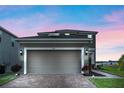 Lovely two-story home with a two-car garage, brick driveway, and manicured landscaping against a colorful sunset sky at 958 Anna Pl, Davenport, FL 33837