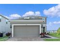 Charming two-story home with a gray two-car garage, brick driveway and manicured landscaping under a bright blue sky at 958 Anna Pl, Davenport, FL 33837