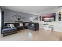 Spacious living room featuring tile flooring, a plush gray sofa, and a large wall-mounted television at 958 Anna Pl, Davenport, FL 33837