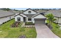 Beautiful two-story home with gray shingle roof, landscaping, and brick driveway at 960 Ladera Ranch Rd, Poinciana, FL 34759