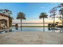 Relaxing poolside view with palm trees and serene lake views during a colorful sunset at 11900 Lake Butler Blvd, Windermere, FL 34786