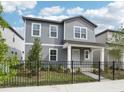 Charming two-story home with gray siding and a well-manicured front yard enclosed by a classic black metal fence at 2437 Zuni Rd, St Cloud, FL 34771