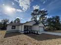 New construction home featuring a white exterior, black accents, and a two-car garage at 702 Marion Oaks Manor, Ocala, FL 34473