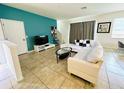 Living room with white sectional sofa and teal accent wall at 840 Las Fuentes Dr, Kissimmee, FL 34746